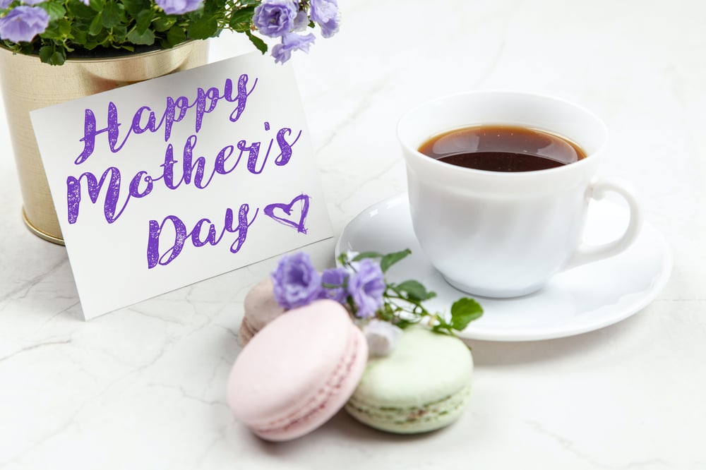 white ceramic teacup next to a card that reads "Happy Mother's Day"