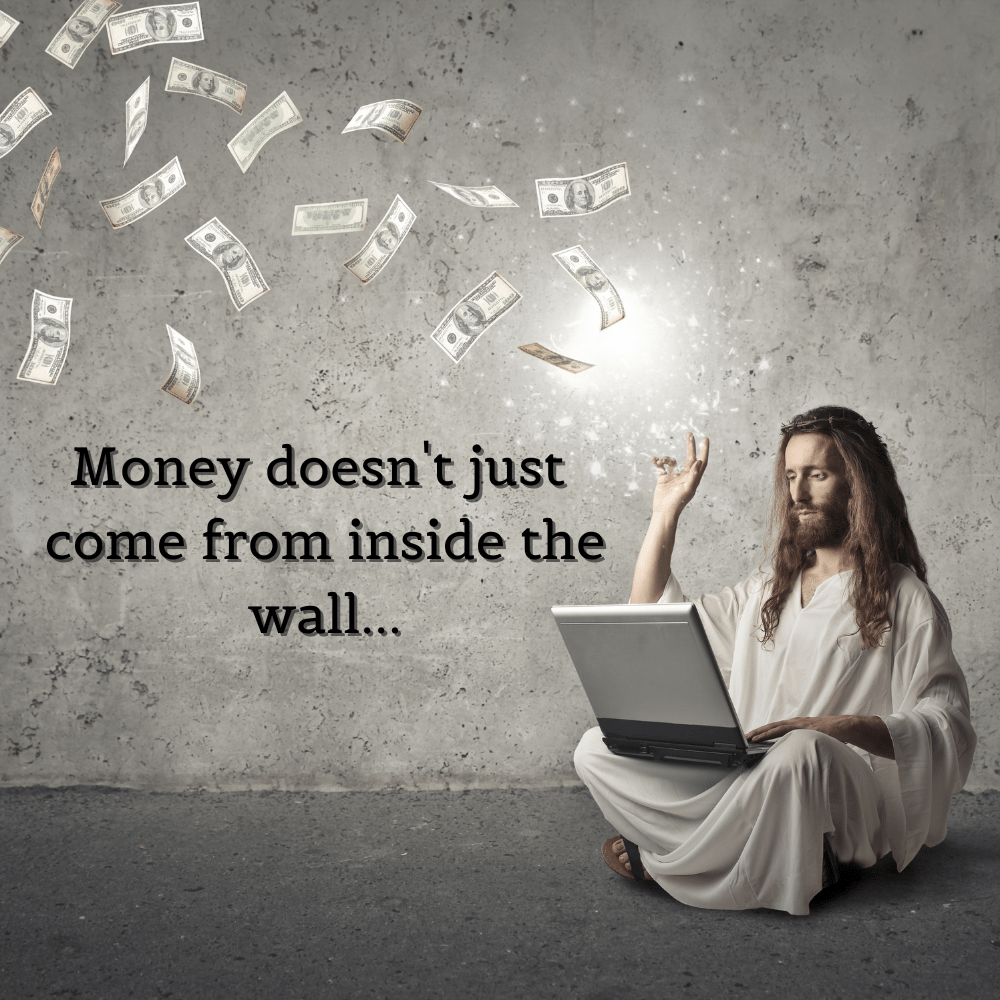 a holy man sitting on the ground conjures money from a laptop
