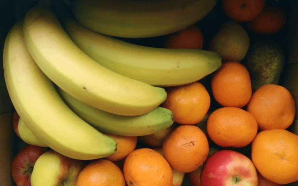 Box of fruit including bananas, apples and oranges