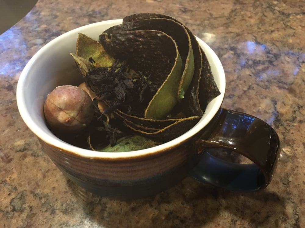 A mug filled with avocado pits and peels for natural dyeing.