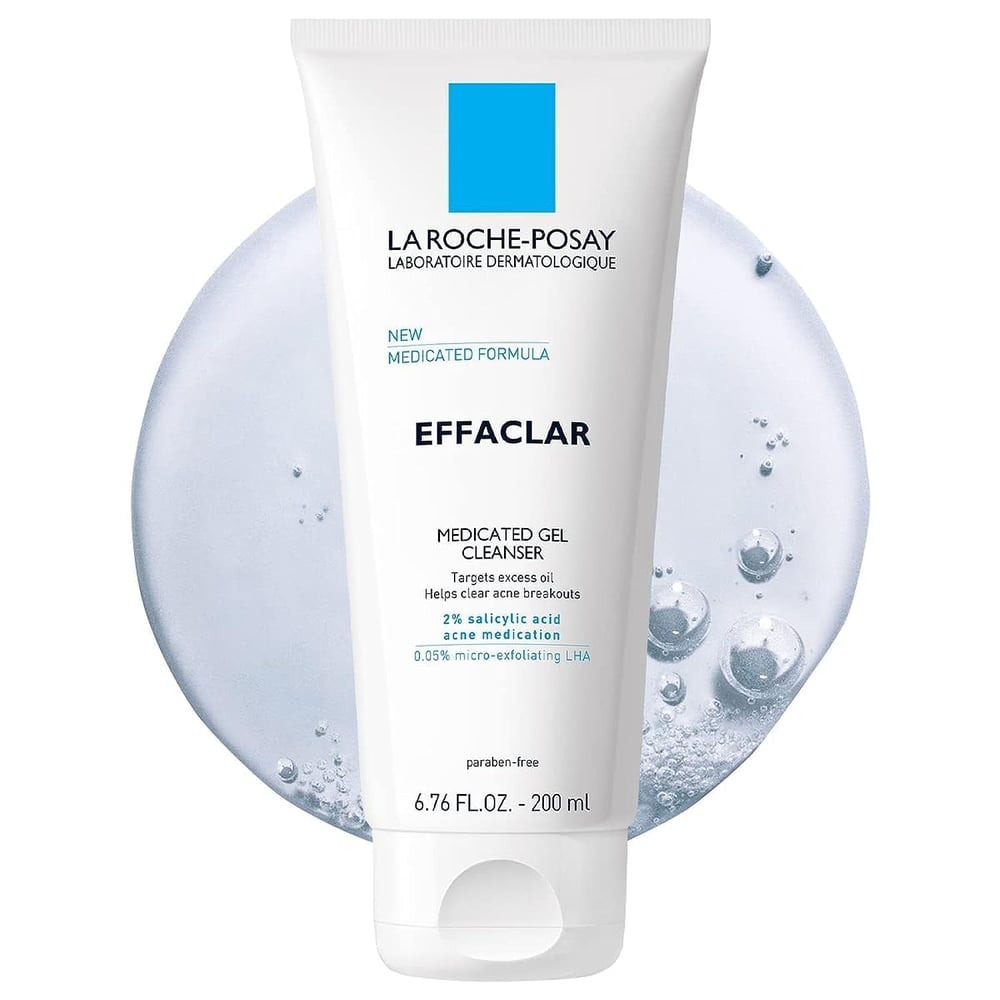 A tube of La Roche-Posay Effaclar Medicated Gel Cleanser is centered on a white background with a translucent gel splash, highlighting 2% salicylic acid for blackhead control and stating it is paraben-free.