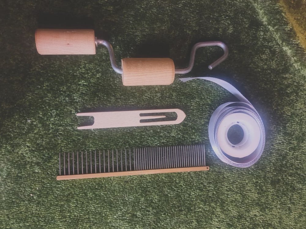 A twine twister, a length of ribbon and some sellotape, a wooden loom shuttle, and a metal comb with two different tooth spacings.