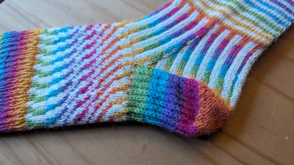 Knitted sock in bright rainbow and white stripes