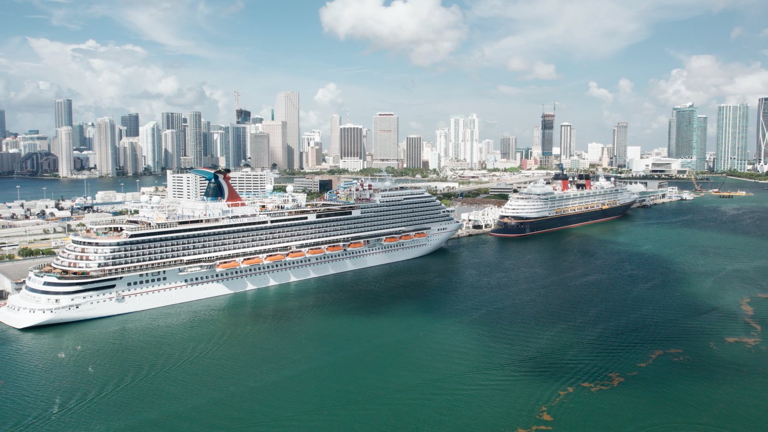 Cruise ships at port of Miami with downtown skyline in background.