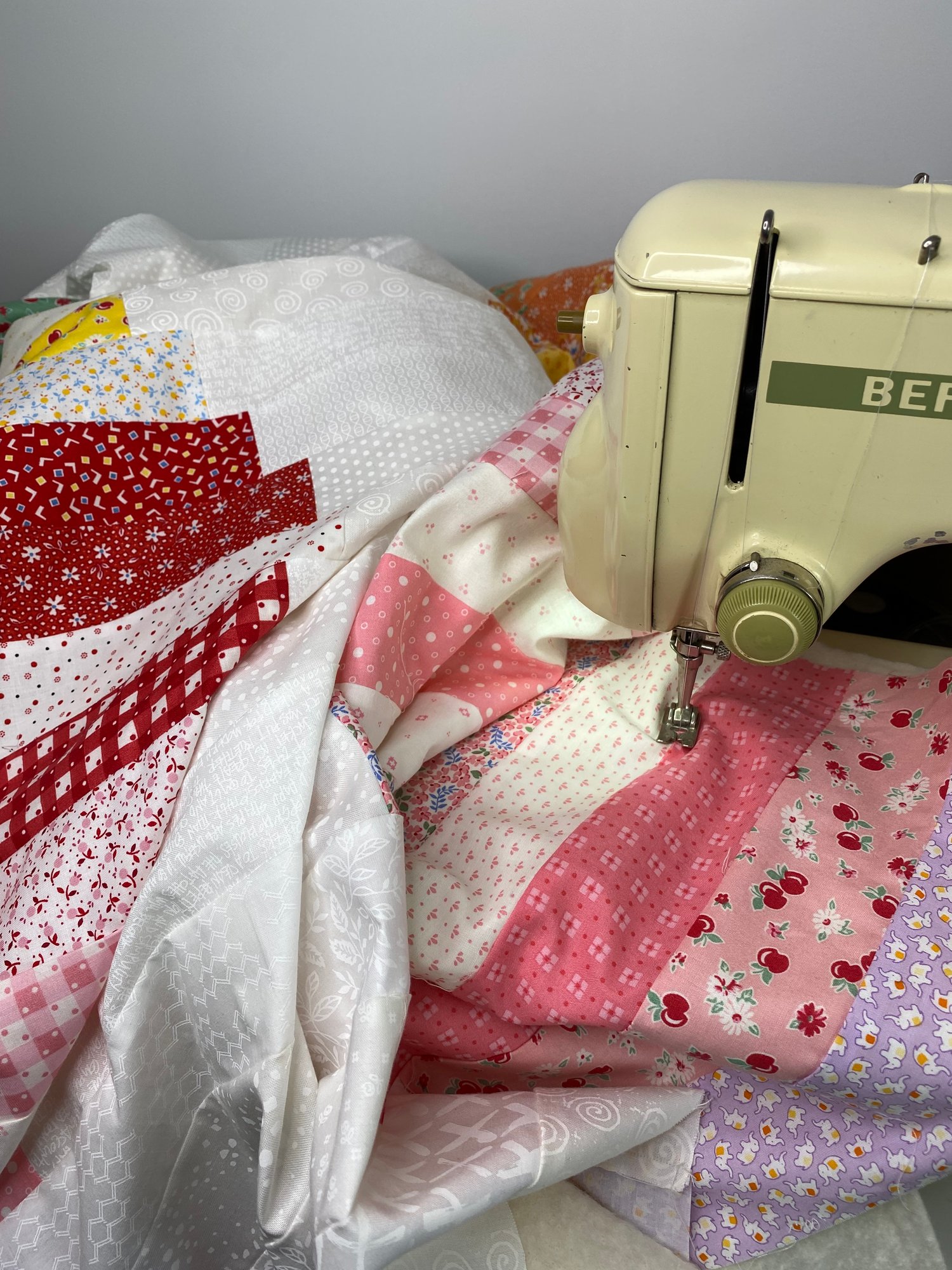 An antique Bernina Sewing Machine in the process of quilting a modern patchwork quilt top.