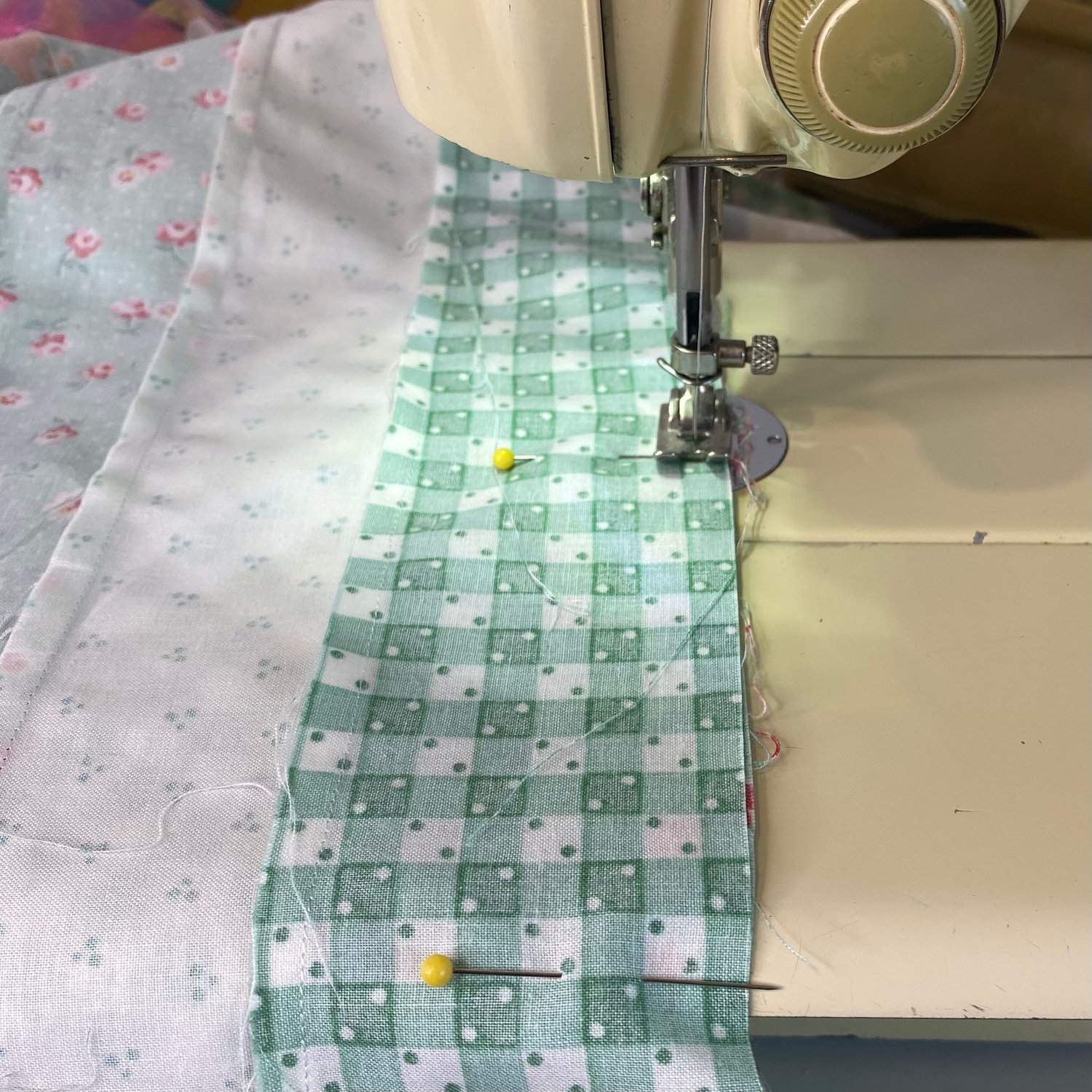 Tips for maintaining a quarter inch seam allowance even when you don’t have a 1/4” quilting foot for your sewing machine. Picture shows an antique sewing machine sewing a 1/4” seam allowance on a modern quilt.