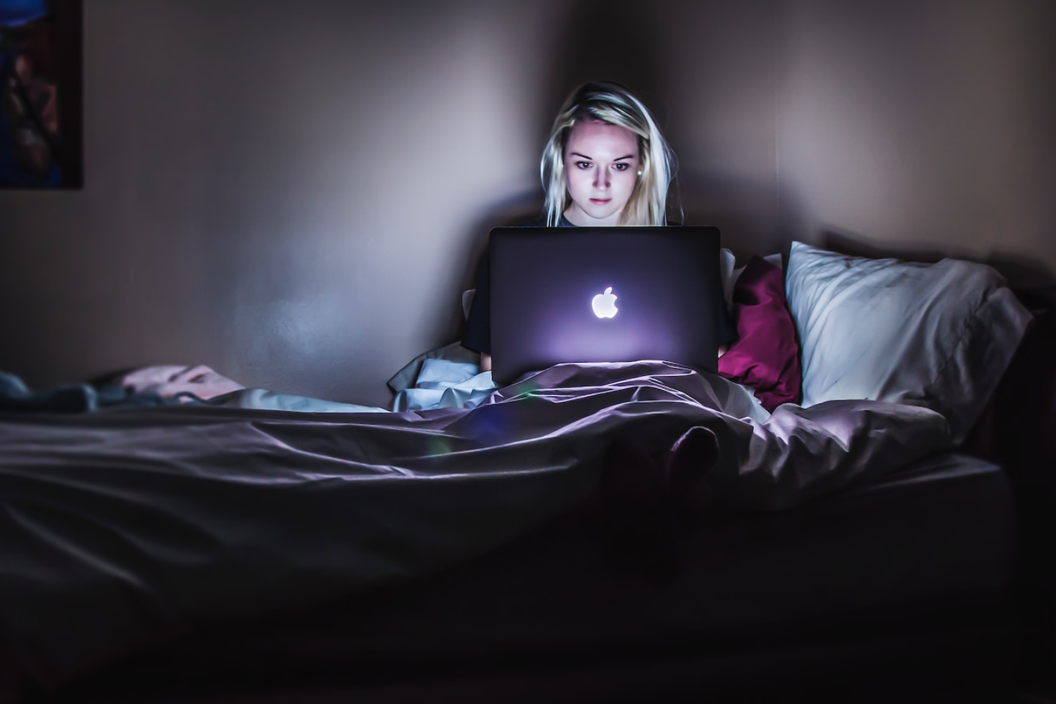 Woman working late at night in her bed on her macbook laptop