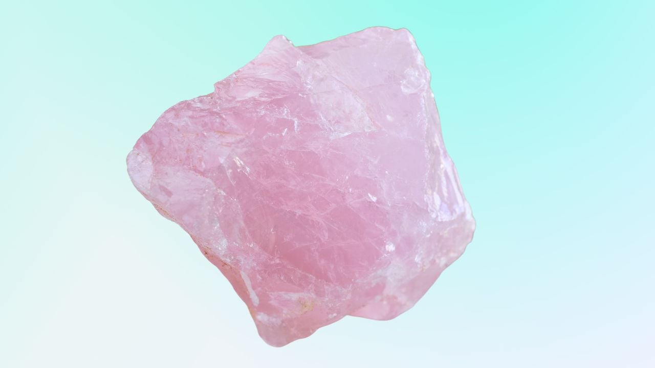 A beautiful rough rose quartz crystal with a pale blue gradient background