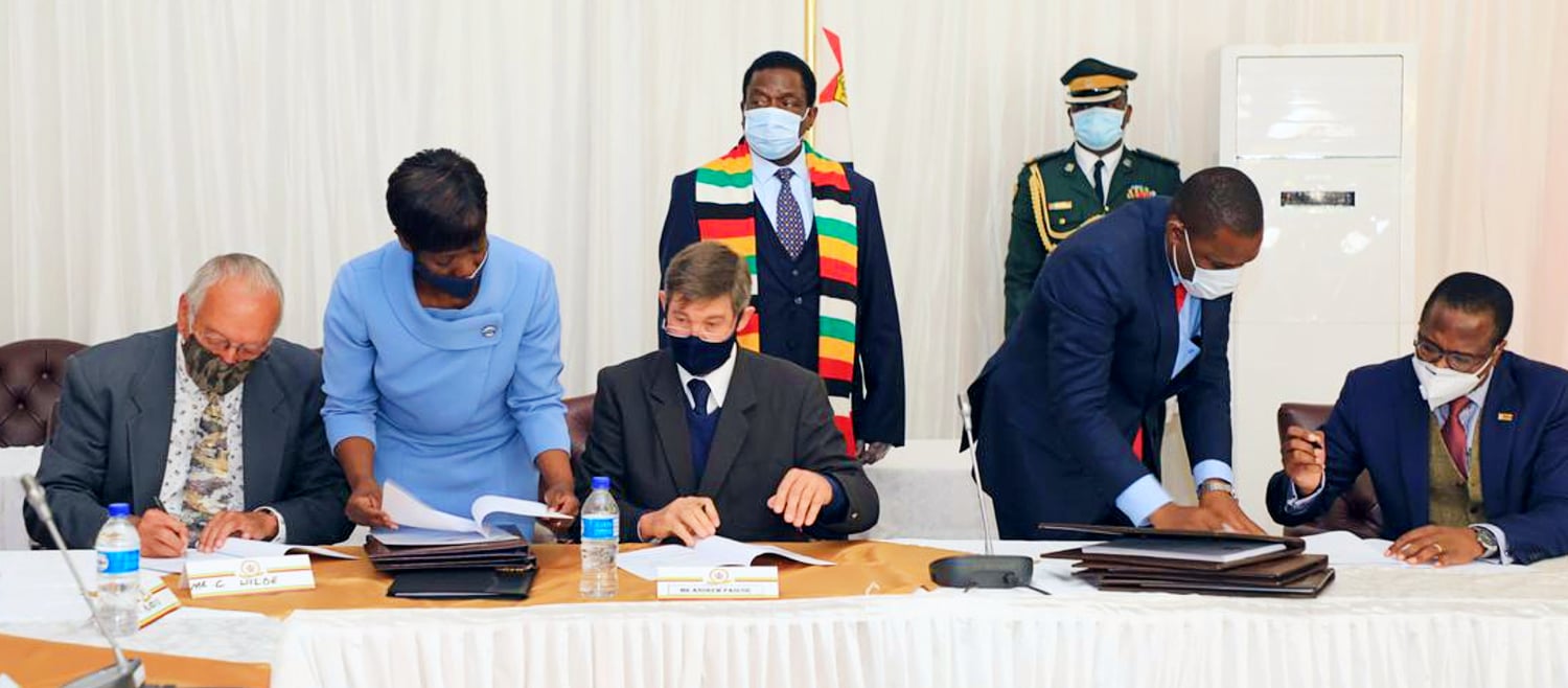 Zimbabwean President Emmerson Mnangagwa (left, rear) and Professor Mthuli Ncube, Zimbabwe's Finance Minister (on the righ,t signing) at a signing ceremony for the compensation agreement for white farmers.