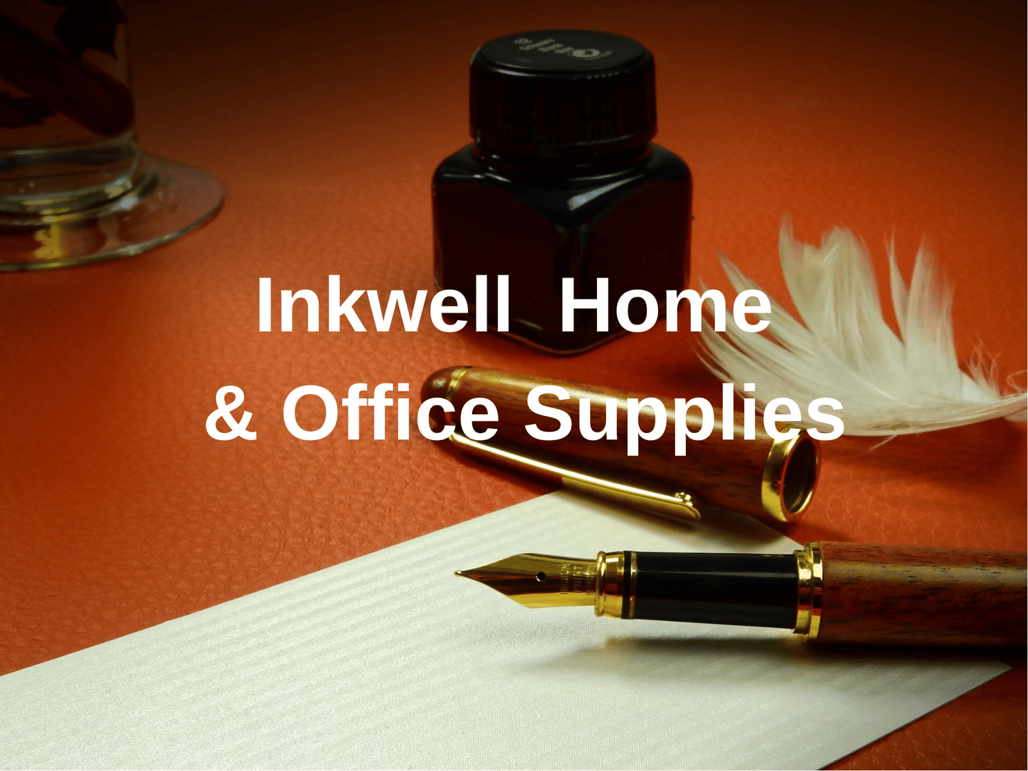 This image shows an office desk with an inkwell, fountain pen, and a document on the rusty orange leather topped desk with a white feather next to the fountain pen, With the words Inkwell office Supplies displayed across the front.