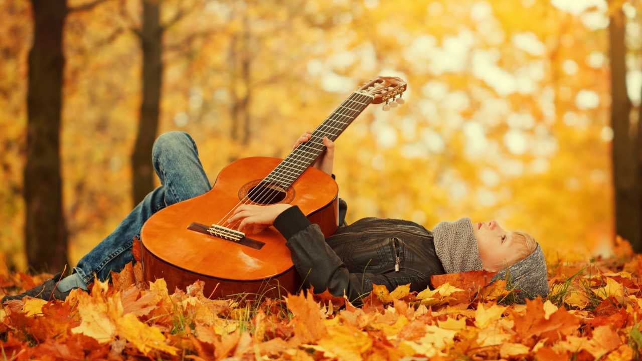girl with classical guitar laying in leaves