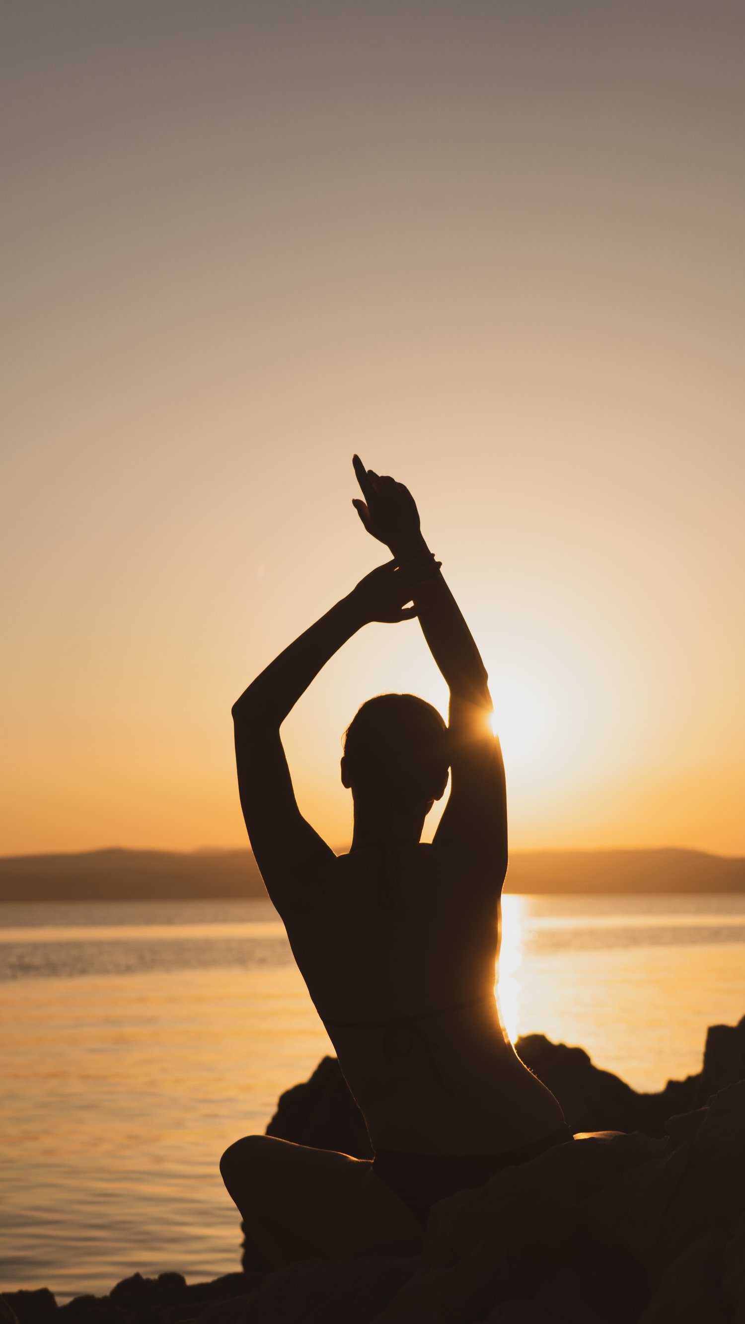 silhouette view of woman doing yoga at sunset on the beach