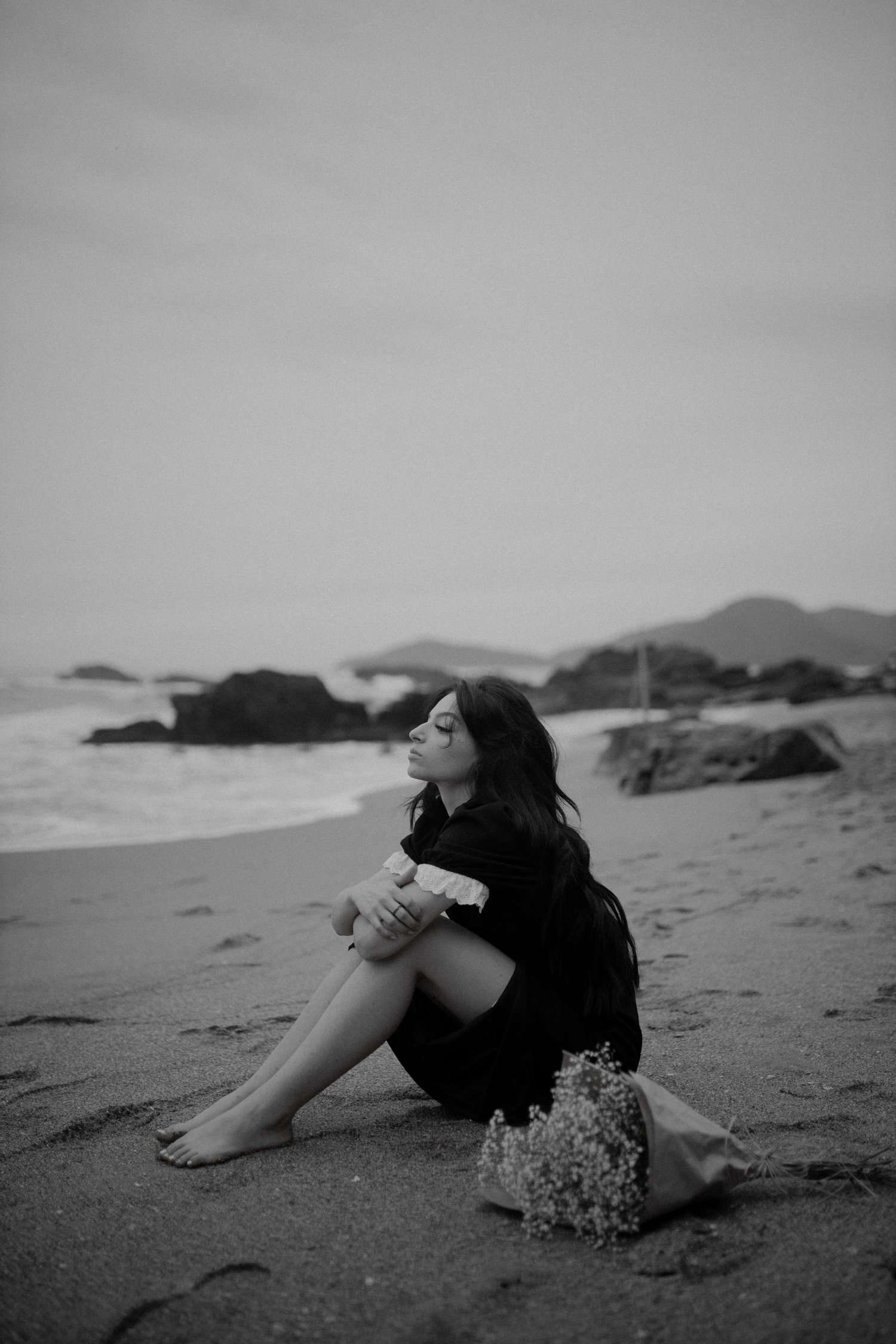 woman sitting on beach black and white