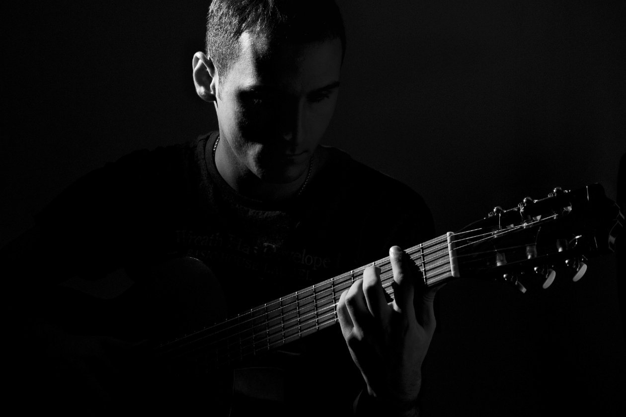 man playing classical guitar in the dark