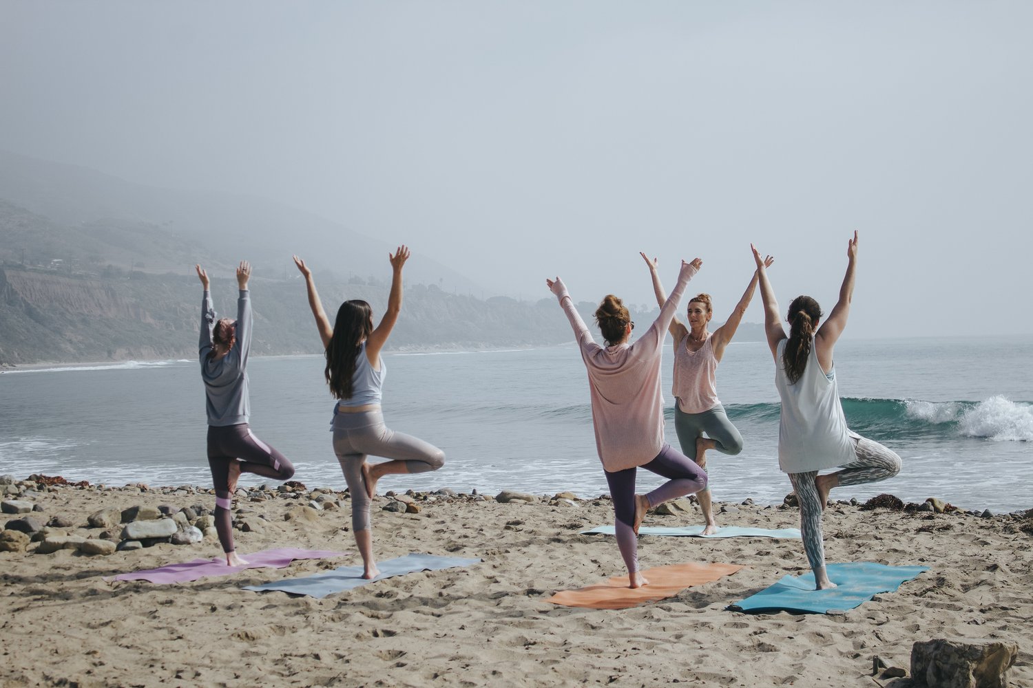 a group of women doing yoga on the beach