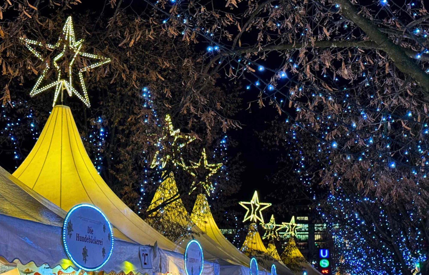 The Christmas market at Jungfernstieg is a captivating tapestry of enchantment, destined to linger in the memory of all who step into its festive embrace. Nestled within the magnificent Alster location, the market radiates in golden splendor, casting a warm glow that transforms the boulevard into a haven of holiday delight. The air is perfumed with the comforting scents of mulled wine and cinnamon, creating an aromatic symphony that accompanies visitors along the enchanting journey.  Here, fine shopping opportunities abound, transforming the act of gift-giving into a joyous experience. The market unfolds its atmospheric hours with an attractive program that weaves a spell of merriment and wonder. Under the starry sky, the landscape transforms into a winter playground, inviting all to partake in the cool exhilaration of ice-skating, a timeless activity that adds an extra layer of magic to the festivities.  For arts and crafts enthusiasts, the stalls reveal a treasure trove of fantastical finds. Each item, a testament to the boundless creativity of local artisans, beckons to be discovered amid the festive allure. As a special treat, five imaginatively decorated fairytale ships anchor in place, becoming whimsical sentinels that enhance the enchanting ambiance of the market.  In the pulsating heart of Hamburg, the Christmas market at Jungfernstieg becomes a portal to a glittering winter landscape. Tradition and modernity intertwine in harmonious unity, creating an atmosphere that transcends time. The elegant white design of the market becomes a canvas for the festive lights, and its picturesque location on the shores of the Binnenalster provides a backdrop that invites all to linger and savor the beauty of the season.  This is not just a market; it is a manifestation of Christmas magic, a special kind that transforms Jungfernstieg into the "Weißerzauber" or White Magic. Beyond being a place to experience festive anticipation, it becomes a stage for regional craftsmanship—a paradise for lovers of mulled wine and Christmas gifts. In the pre-Christmas period, Jungfernstieg transforms into a sea of lights and colors that enchant both locals and visitors alike. A visit to this magical realm is more than worthwhile; it is an opportunity to immerse oneself in the Christmas world of Hamburg—a world where the air is filled with joy, the landscape glows with festive lights, and the spirit of the season weaves its spellbinding magic into the very fabric of the city.