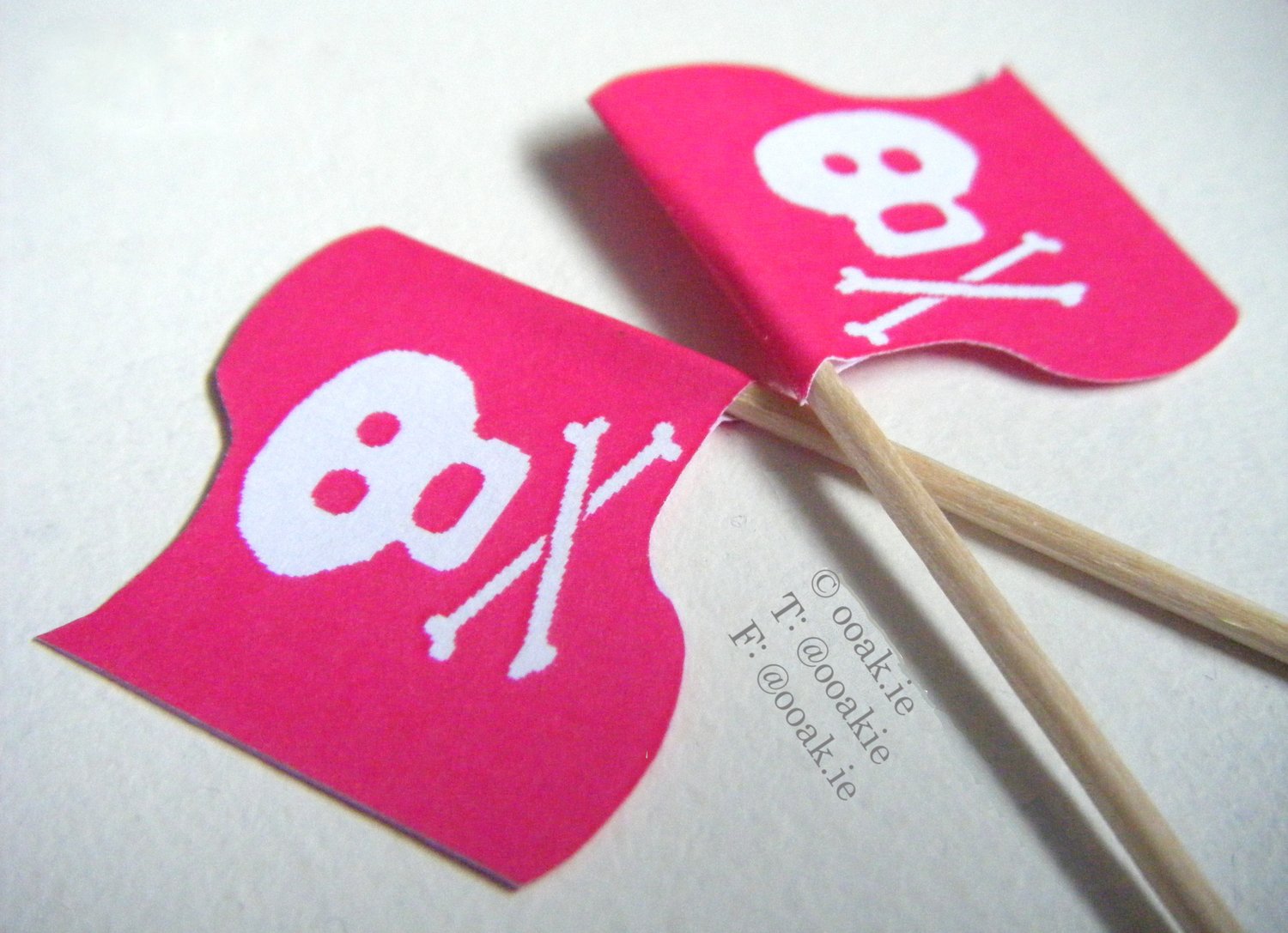 close up of 2 Pink Jolly Roger flags showing mirror image on both sides. white skull and crossbones on bright pink wavy flag.