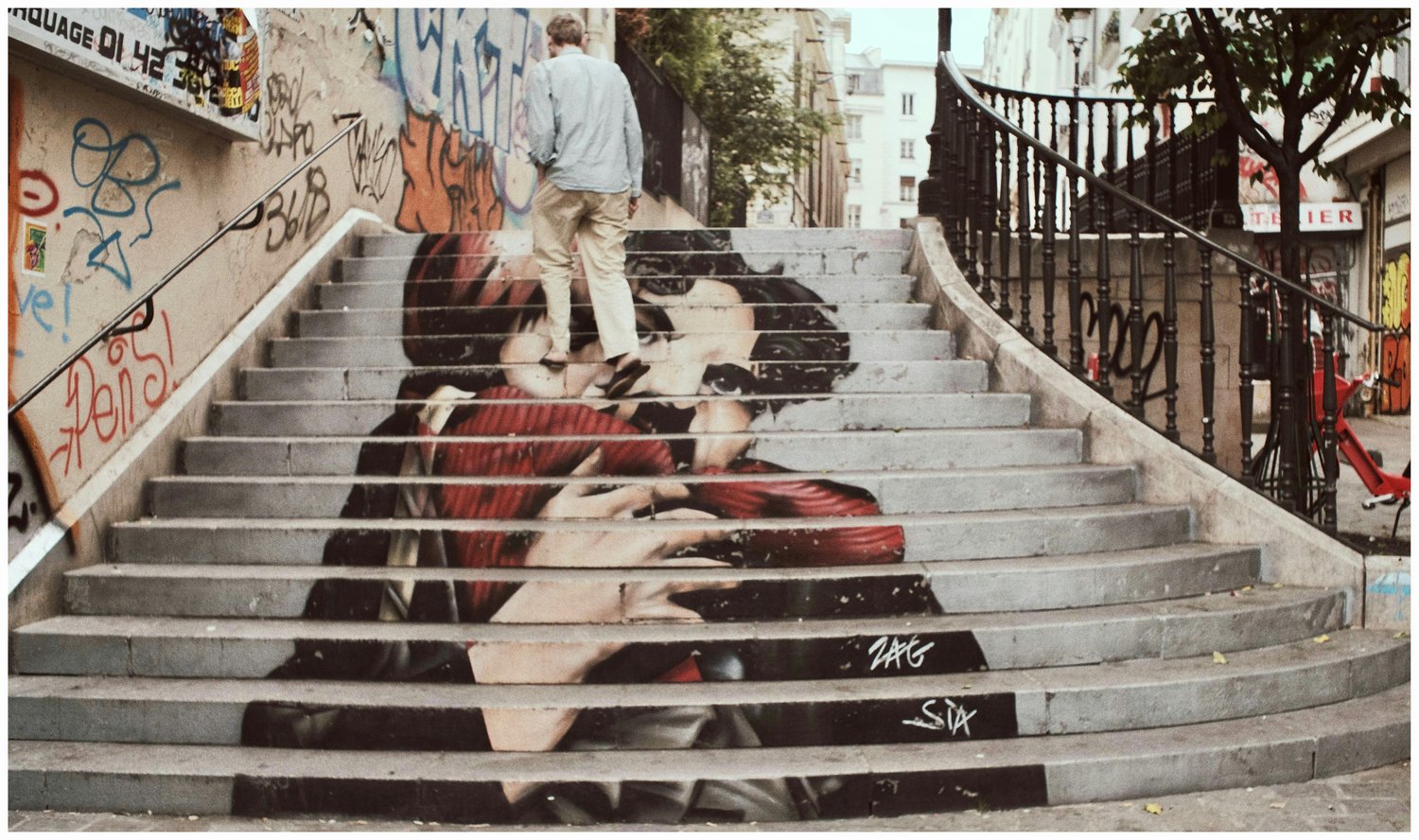 Man walking up stairs that has a mural painted on it.