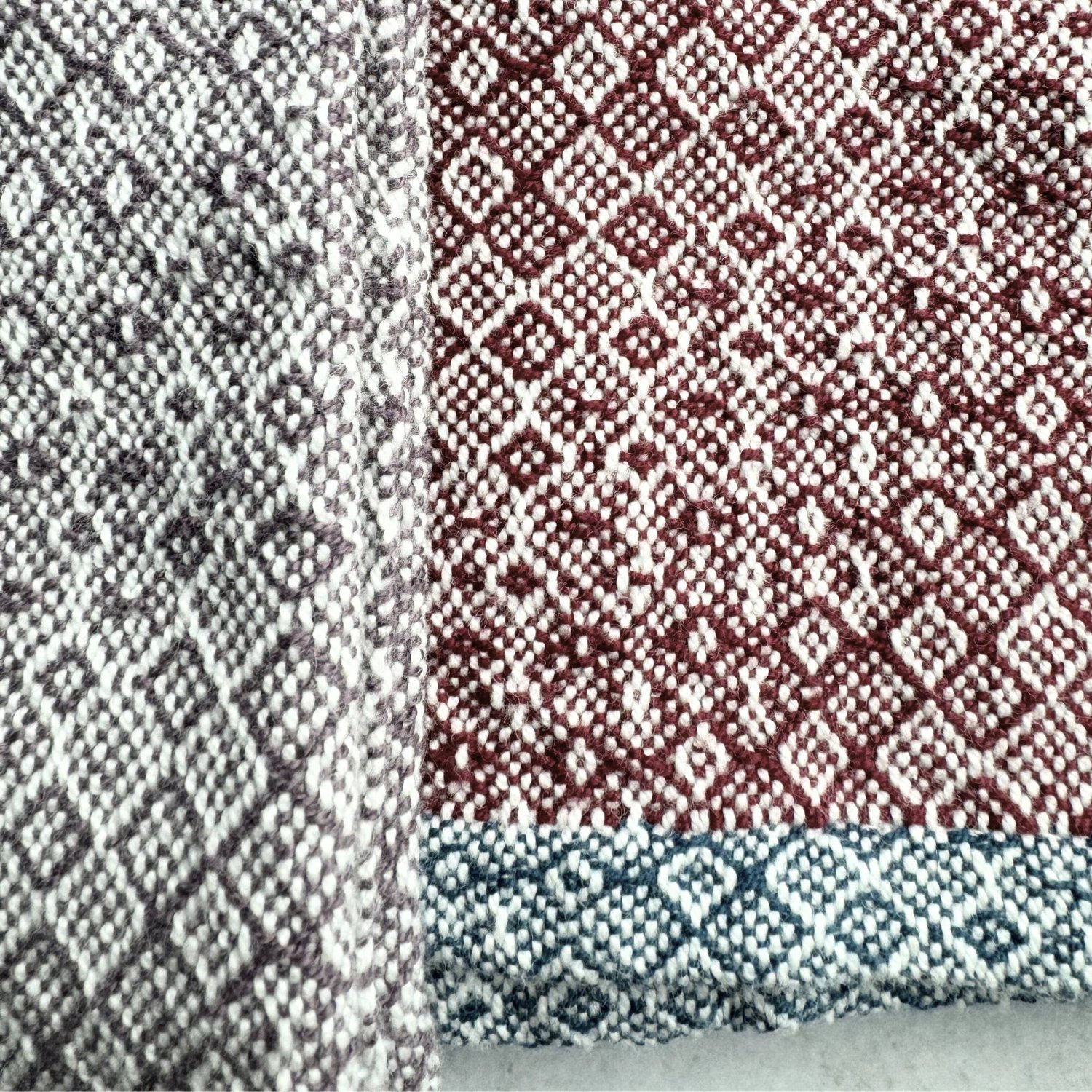 Handwoven dish towels in an advancing twill pattern. one towel is grey and white, the other is wine an white with a teal hem. Shot is a closeup with a slate grey background.