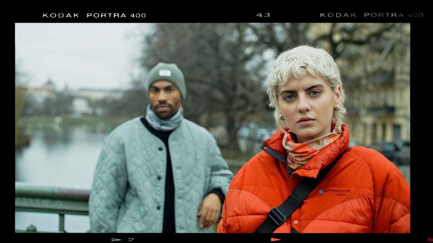 Two models look into camera standing on a bridge.
