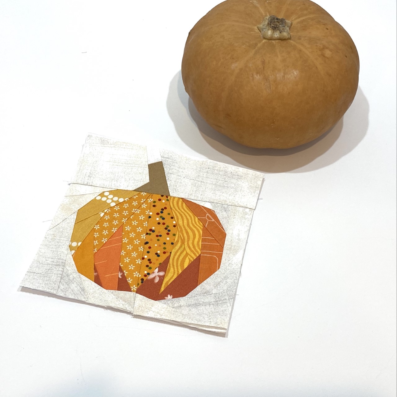 This paper pieced pumpkin quilt block is an example of a pattern that is designed for using up fabric scraps from other quilting projects.
