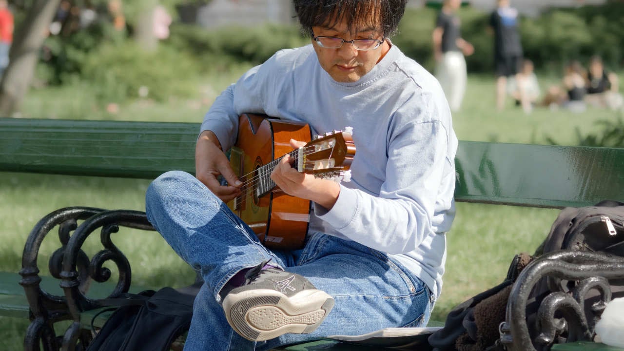 Guitarist reading music on bench