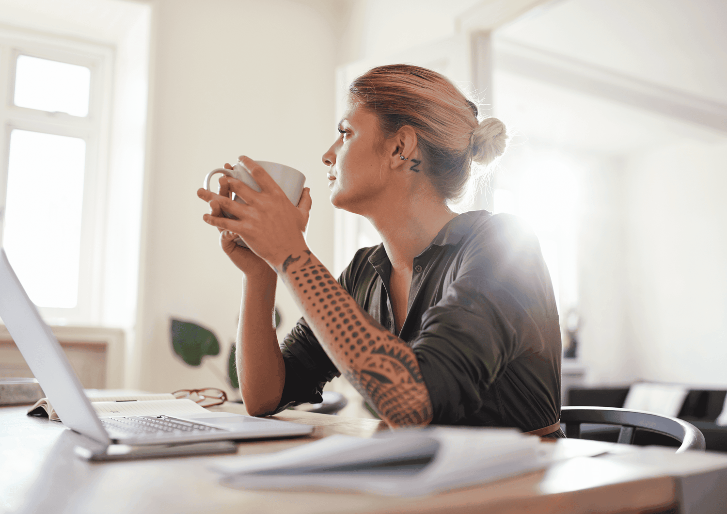 woman at a desk with a laptop holding a cup of coffee