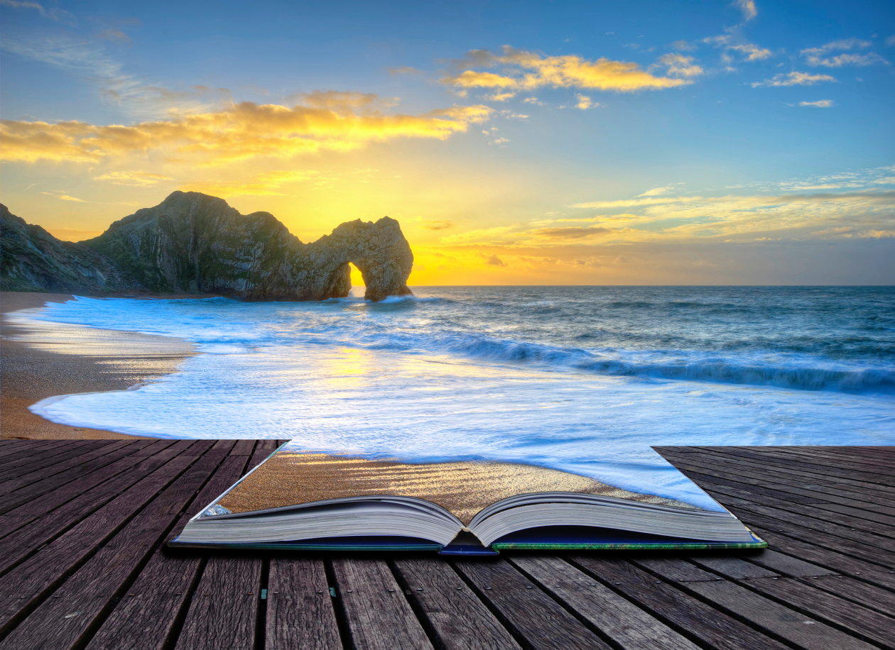 Vibrant sunrise over ocean with rock stack in foreground in the page of an open book, colorful sunset, books, imagination, beach