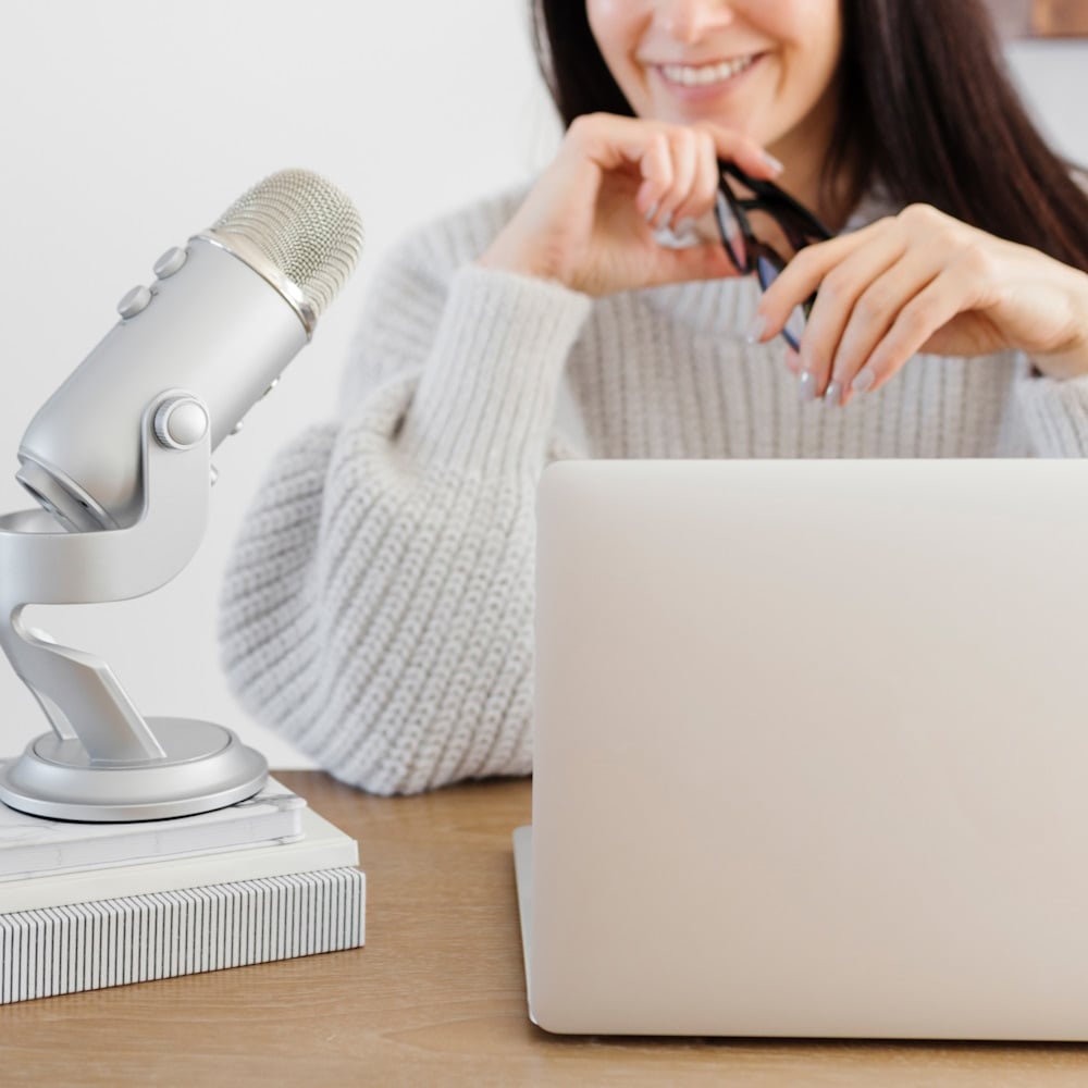 photo of a woman using a computer and podcast mic