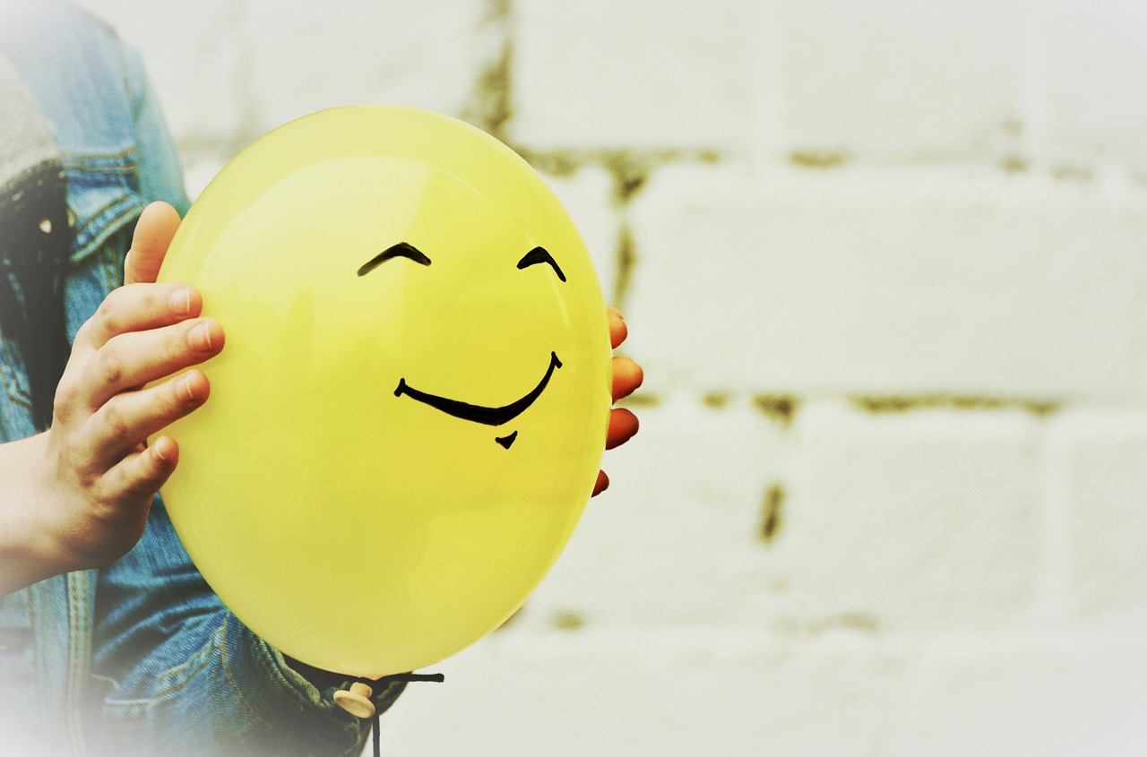 Persona sujetando un globo amarillo sonriente-relax-serenidad