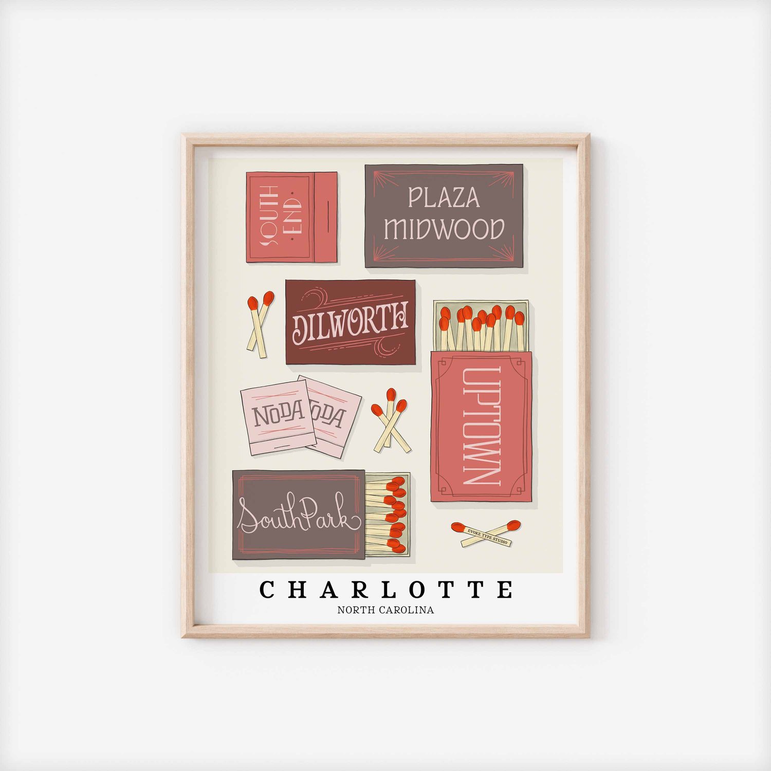 A framed picture of Charlotte, North Carolina neighborhoods drawn in various lettering styles on matchboxes. Artwork has a pink, grey and burgundy color scheme.