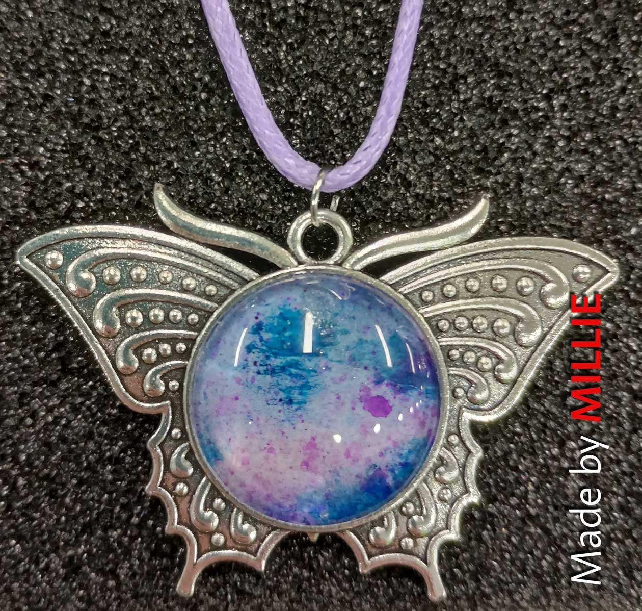 Stainless steel butterfly pendant, with a domed centre, handpainted abstract in blues and purples by Millie