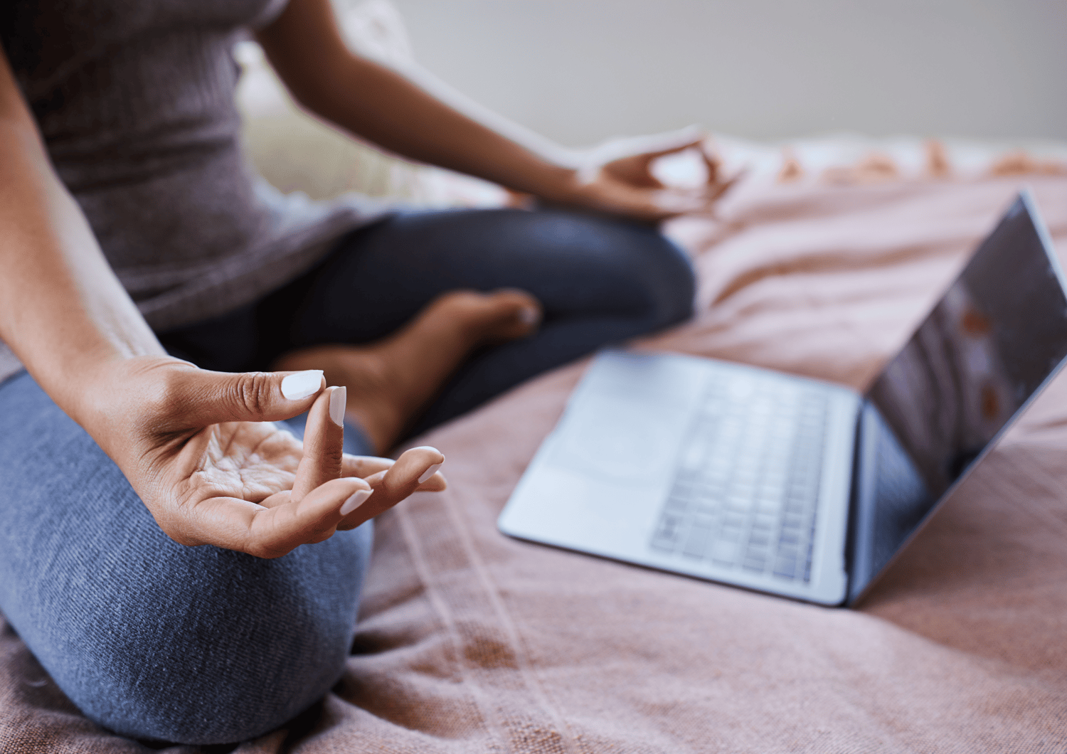 woman sitting in meditation on a mat in front of a laptop