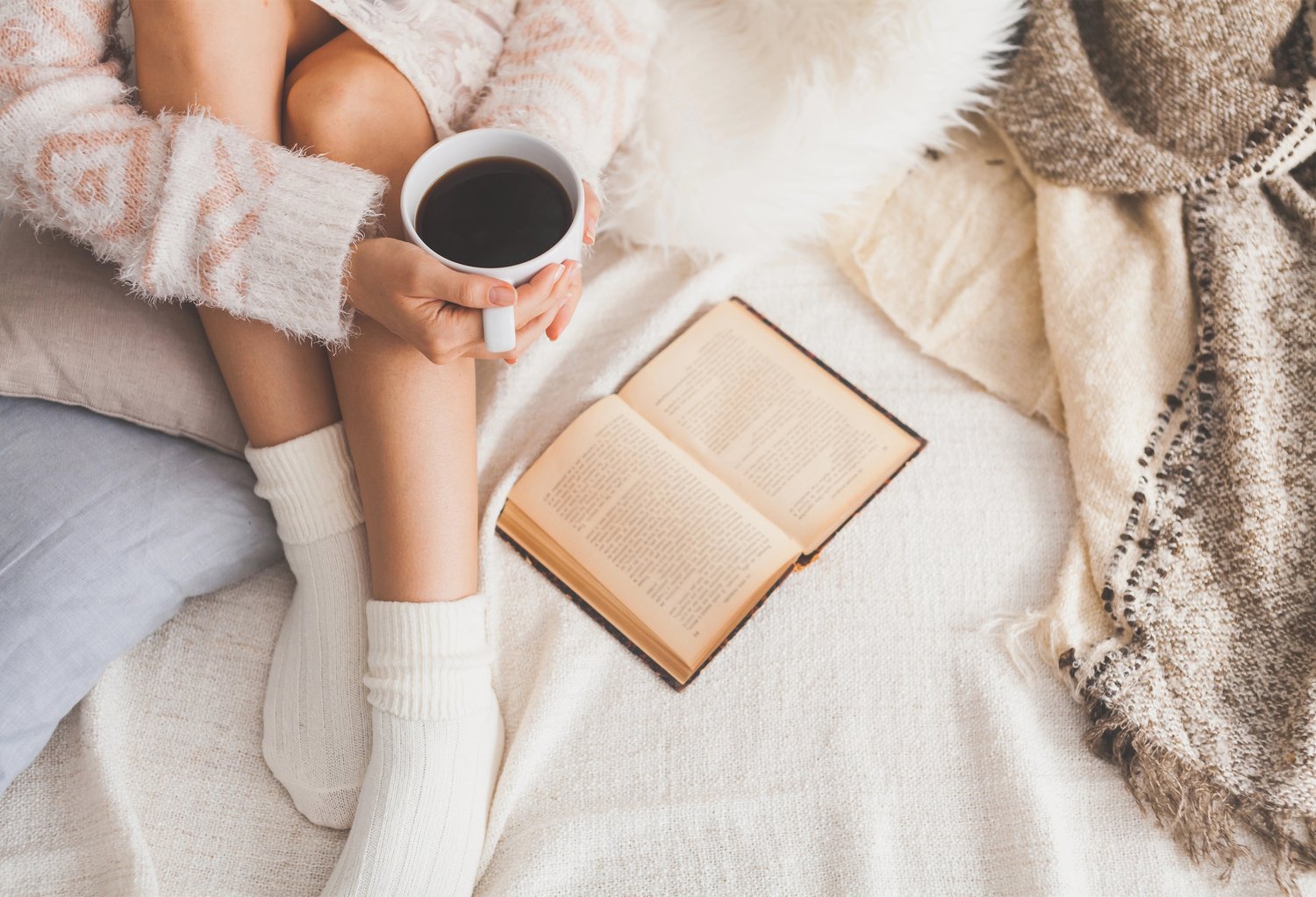 Coffee in hand on a cozy bed reading a romance novel