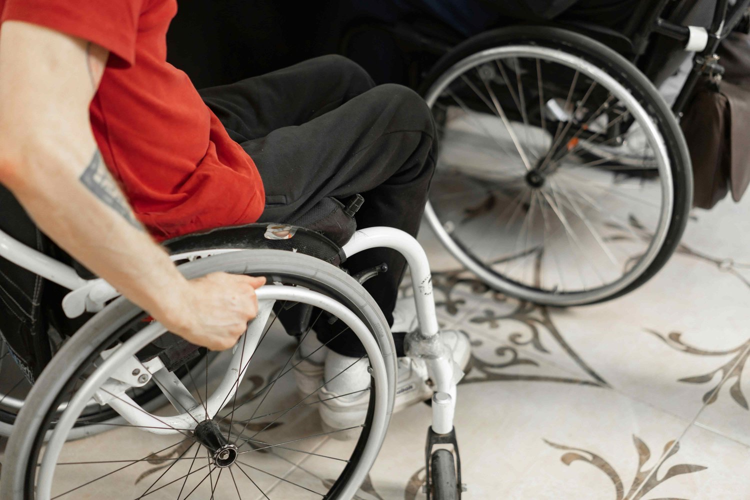a man in a red shirt with his hands on his wheelchair wheels