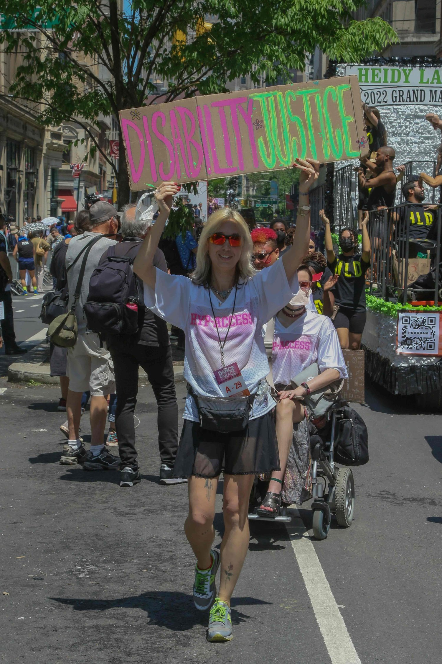 a woman holding a sign that reads "disability justice" at a awareness march