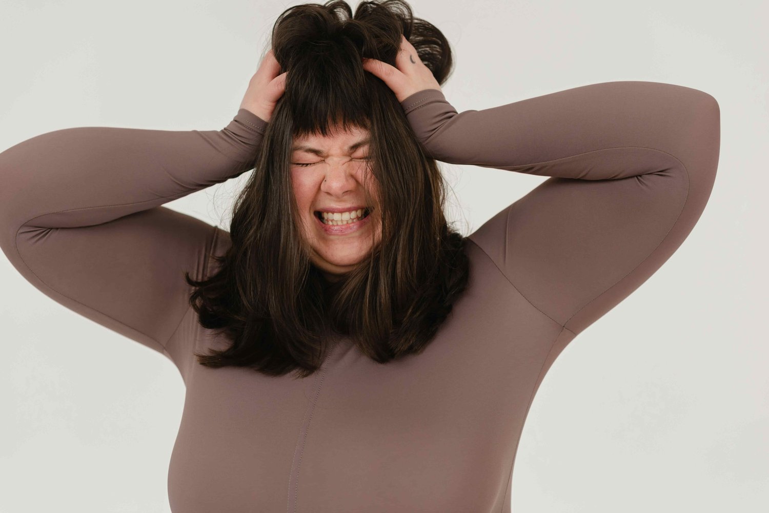 a larger woman, pressing her hands to her head in stress and anger