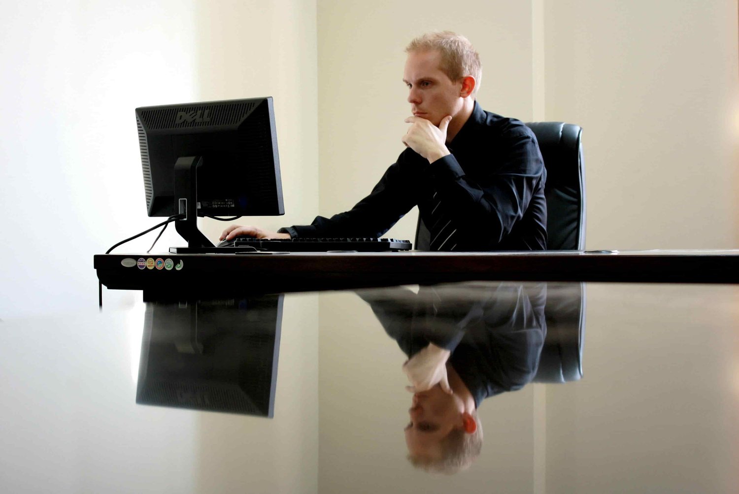 a white man looking at his computer, thinking, with his hand on his chin