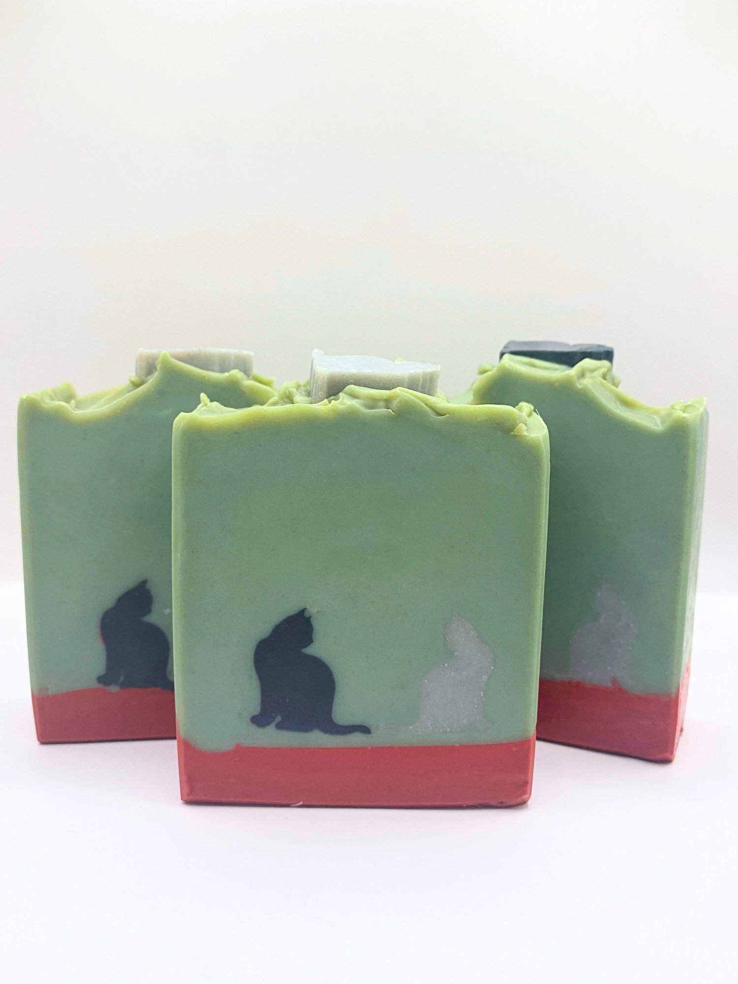 Hemingway's Cats handmade soap shows a black cat and a gray cat sitting on a brick wall in the author's Key West home