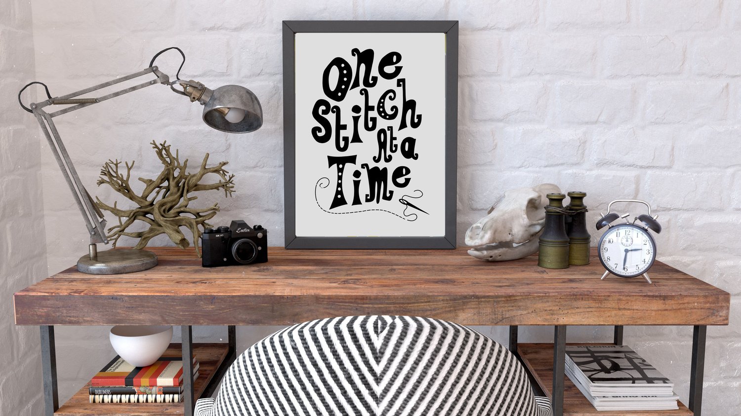 A downloadable print with a hand lettered design which says ‘one stitch at a time’ in black.
