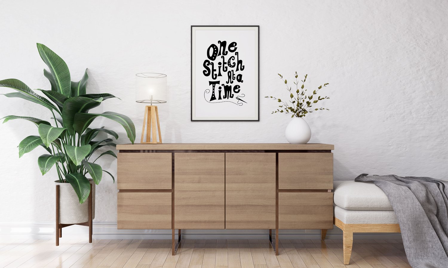 A downloadable print with a hand lettered design which says ‘one stitch at a time’ in black.