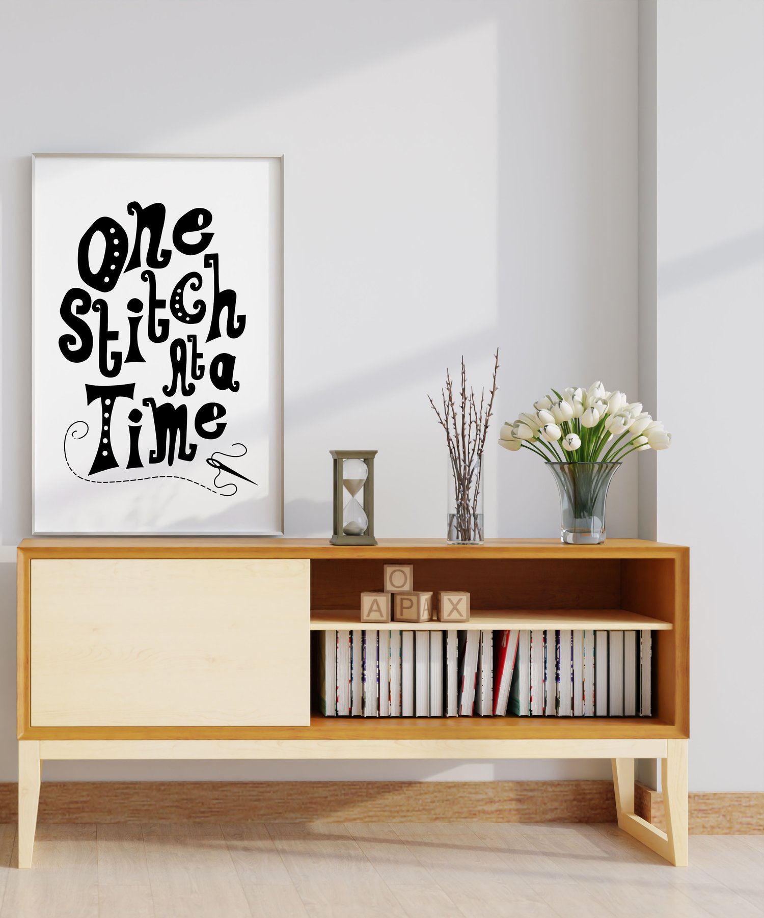 A downloadable print with a hand lettered design which says ‘one stitch at a time’ in black.