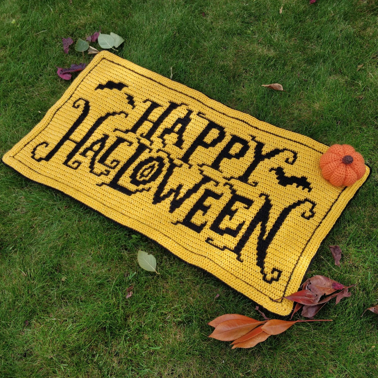 Halloween Banner in black on a yellow background laying on some grass