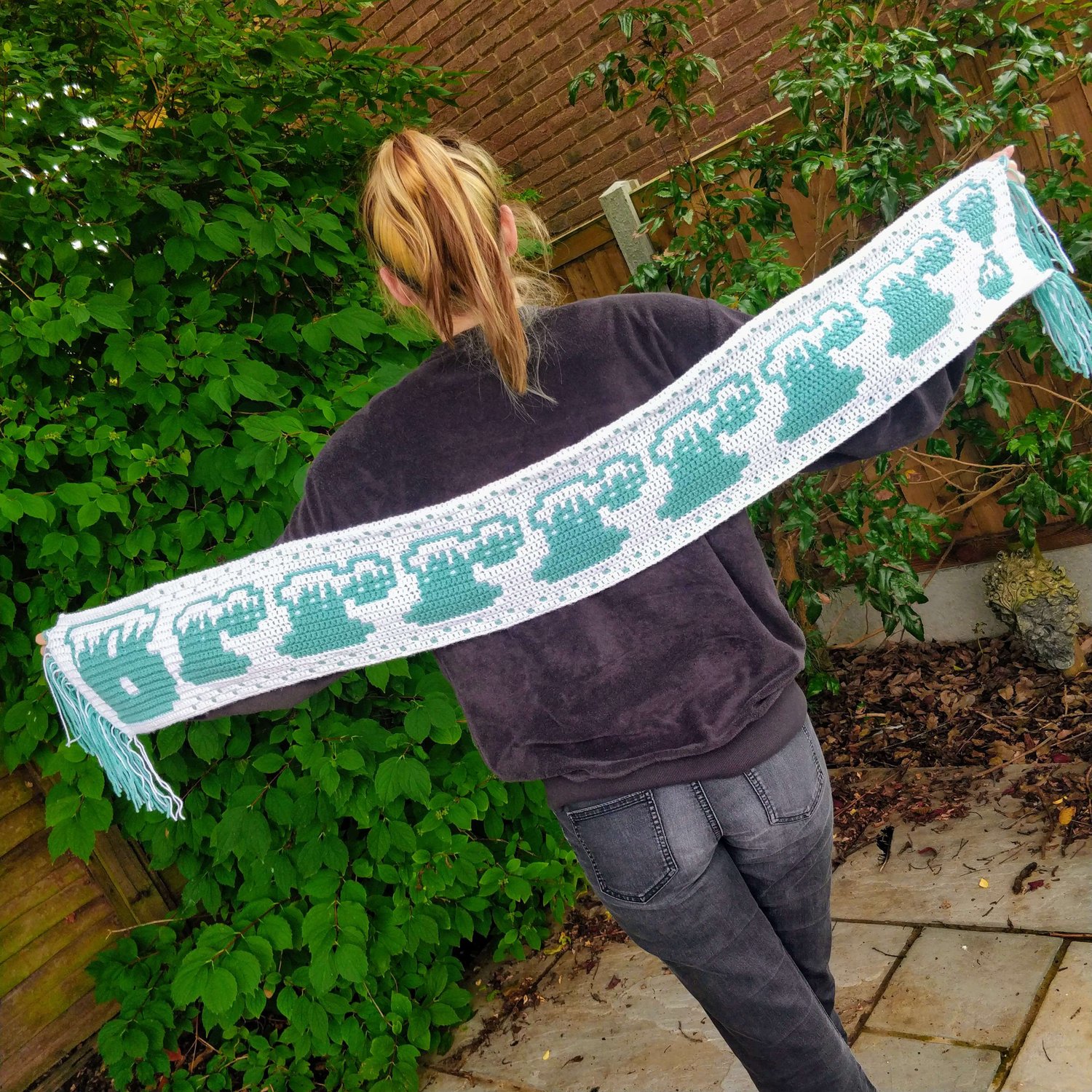 Woman holding out a white and teal scarf with the word BRRRR! across it