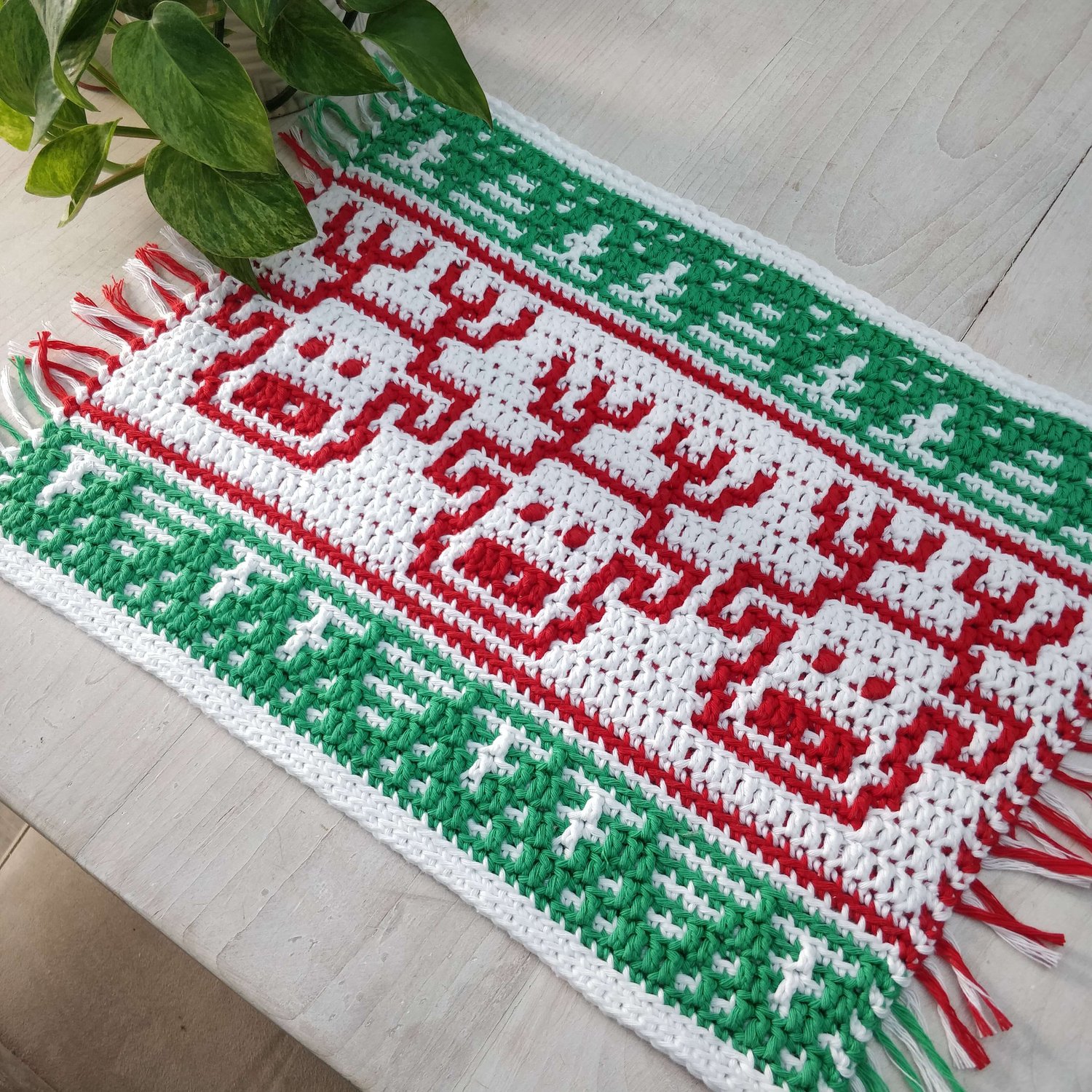 Crocheted placemat with reindeer heads and a fir tree border