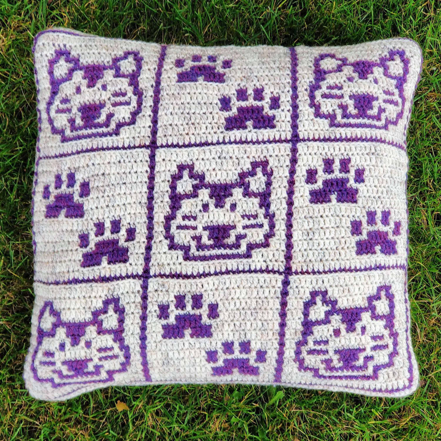 Crocheted cushion split into nine segments with alternating cat head and cat paws