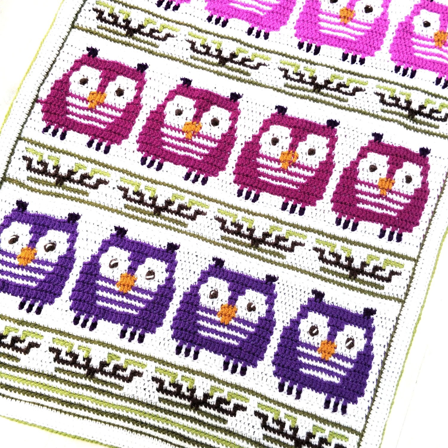 Crochet blanket showing rows of owls with rows of branches in between
