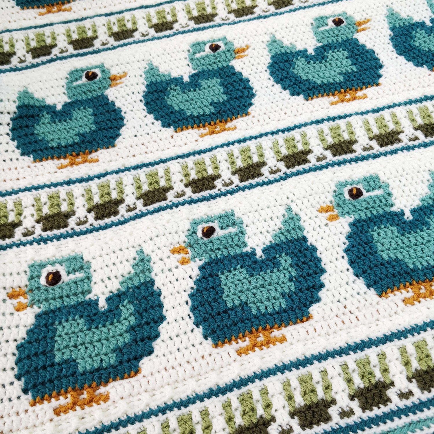 Crochet blanket showing strips of teal mallard ducks with duck week strips in between