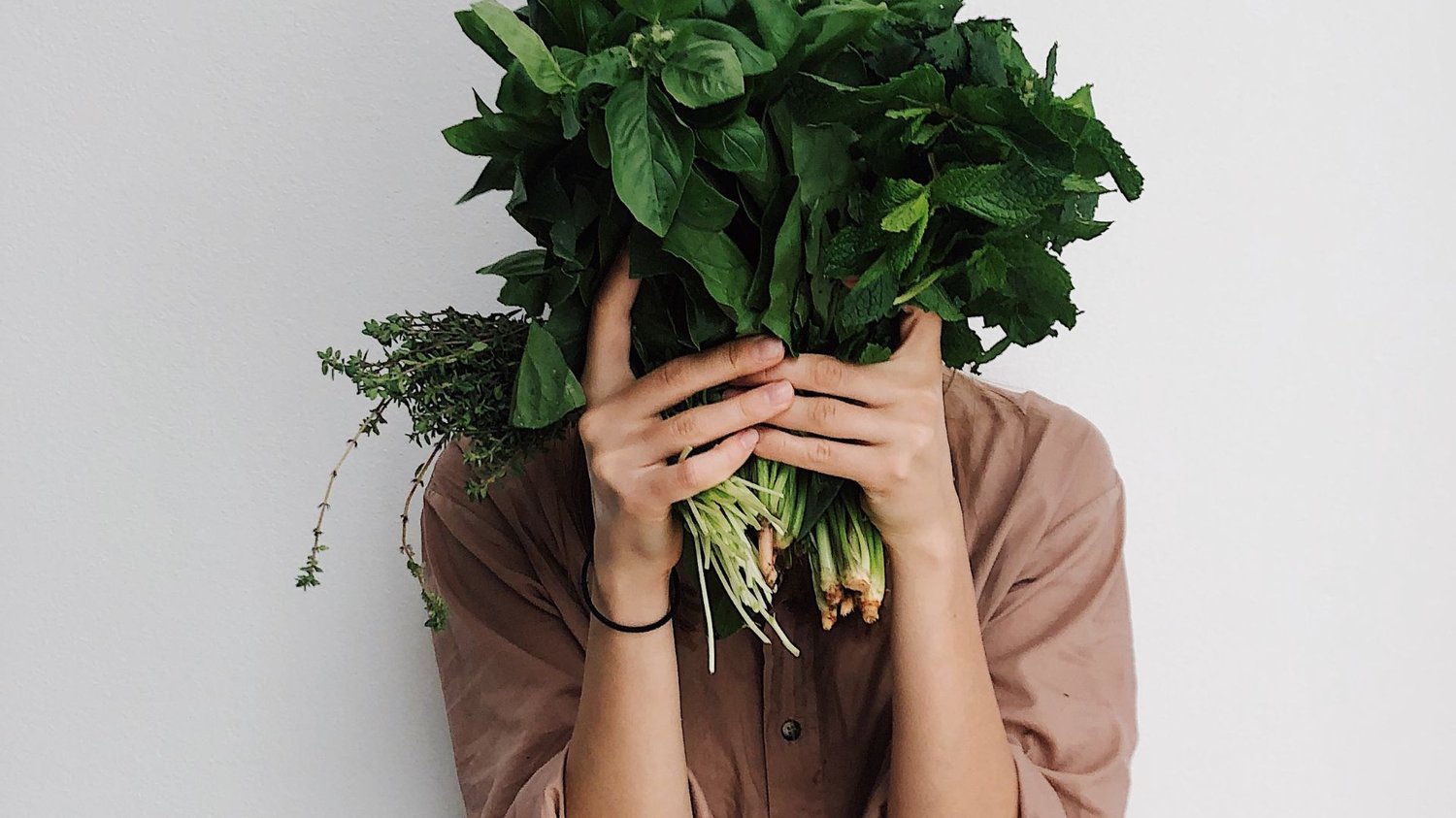 A woman holding greens infront of her face