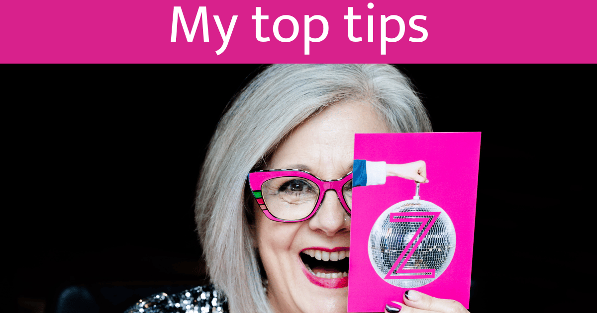 Business owner smiling while using LinkedIn on their laptop, with vibrant disco ball light reflections on their face - representing how your LinkedIn profile can become your 24/7 networking party that attracts ideal clients while you build your business i